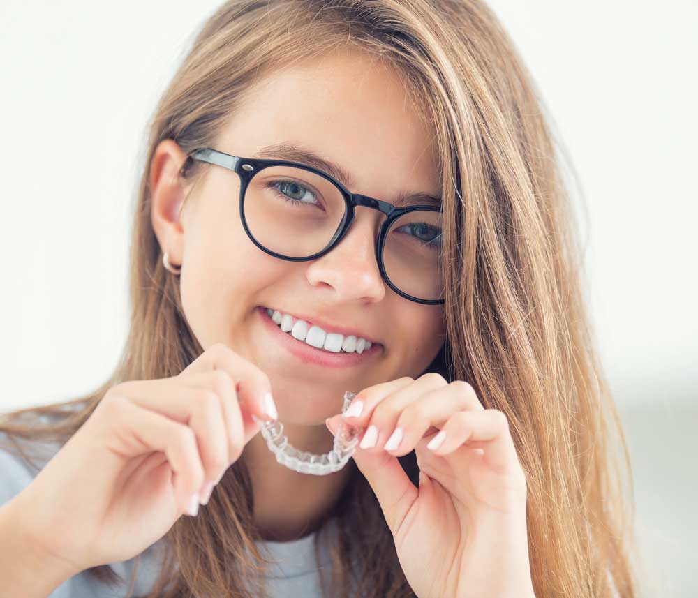 Girl with Invisalign Girl Holding an Invisalign Tray