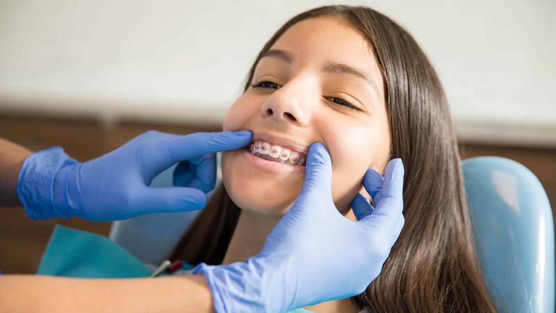 girl with braces being examined by orthodontist