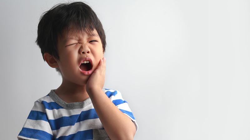 Child holding mouth in pain