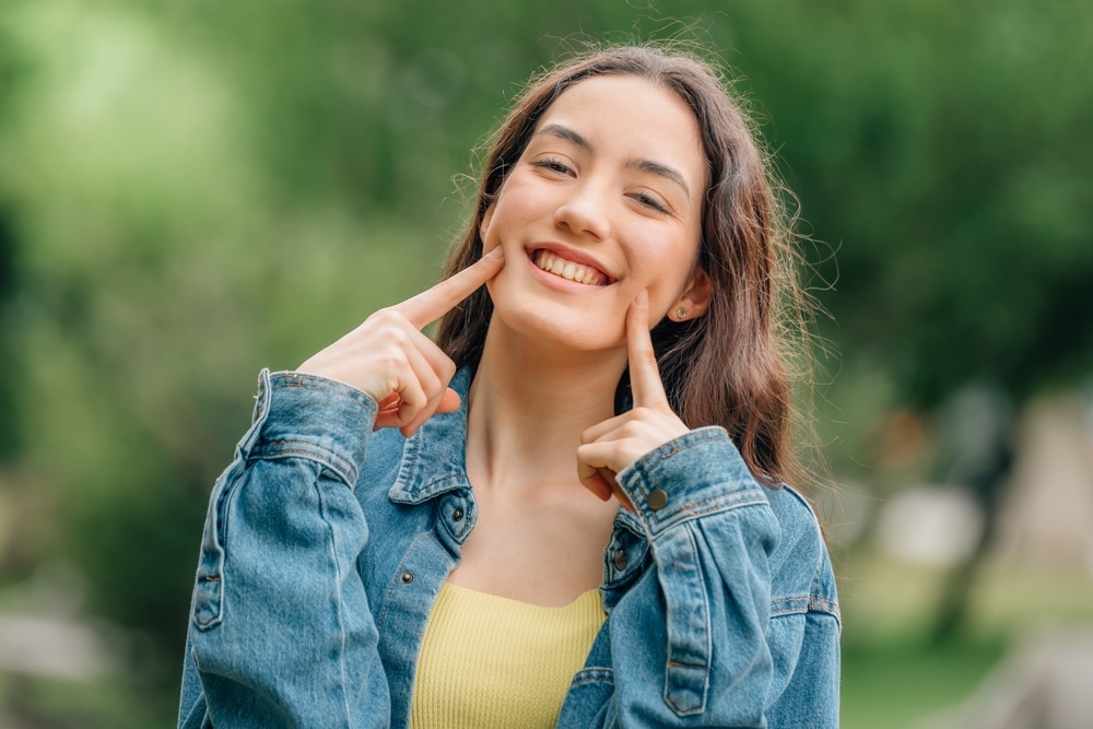 wisdom teeth extractions in St. Charles and Wheaton Smiling girl pointing to her face