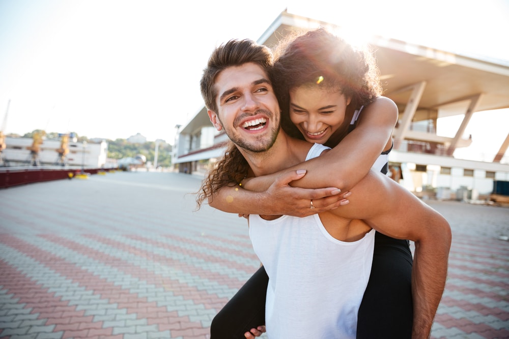 Woman on the back of a man piggyback. DPD smiles in St. Charles and Wheaton Oral Surgery Wheaton and St. Charles